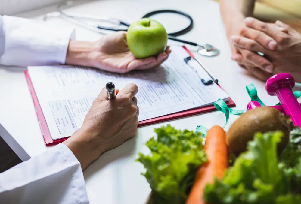 Doctor writing in chart, holding a green apple